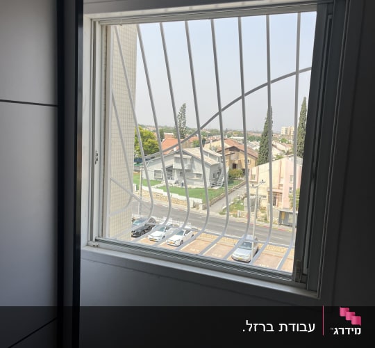 חלון עם סורגים ונוף עירוני בחוץ